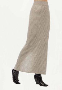Stickad, ribbad midikjol i ljusgrått. Passform design med bred midja, ihop med svarta spetsiga klackstövlar.