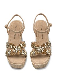 Sandali con tacco a cuneo beige con cinturini incrociati decorati con gemme. Presentano piccole pietre d'oro e cristallo, una soletta imbottita e una suola in stile espadrilles.