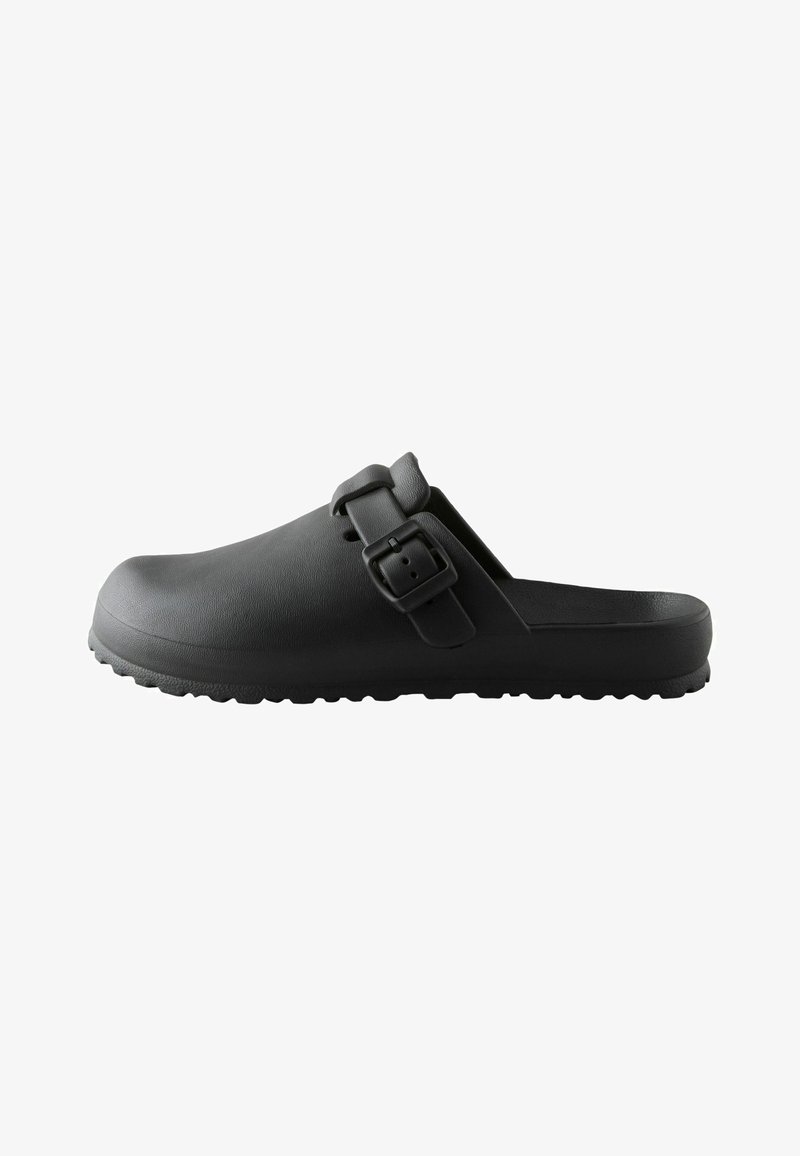 Sabot noir sans fermeture avec semelle texturée et bride ajustable avec boucle carrée, montré de côté sur fond blanc.