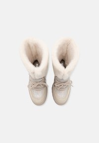 Bottes tan et crème avec une doublure en fausse fourrure, texture lisse, design à lacets et accents métalliques brillants sur la tige.