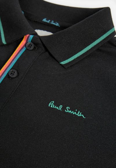 Mustaga polo särk tekstuuritud kangast, millel on roheline krae, mitmevärviline triibuline nööpplaat ja tikand "Paul Smith" logo.