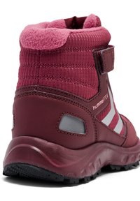 Bota deportiva alta en color burdeos con parte superior de tela texturizada, collar acolchado, tiras de Velcro y suela de goma negra con patrones de tracción.