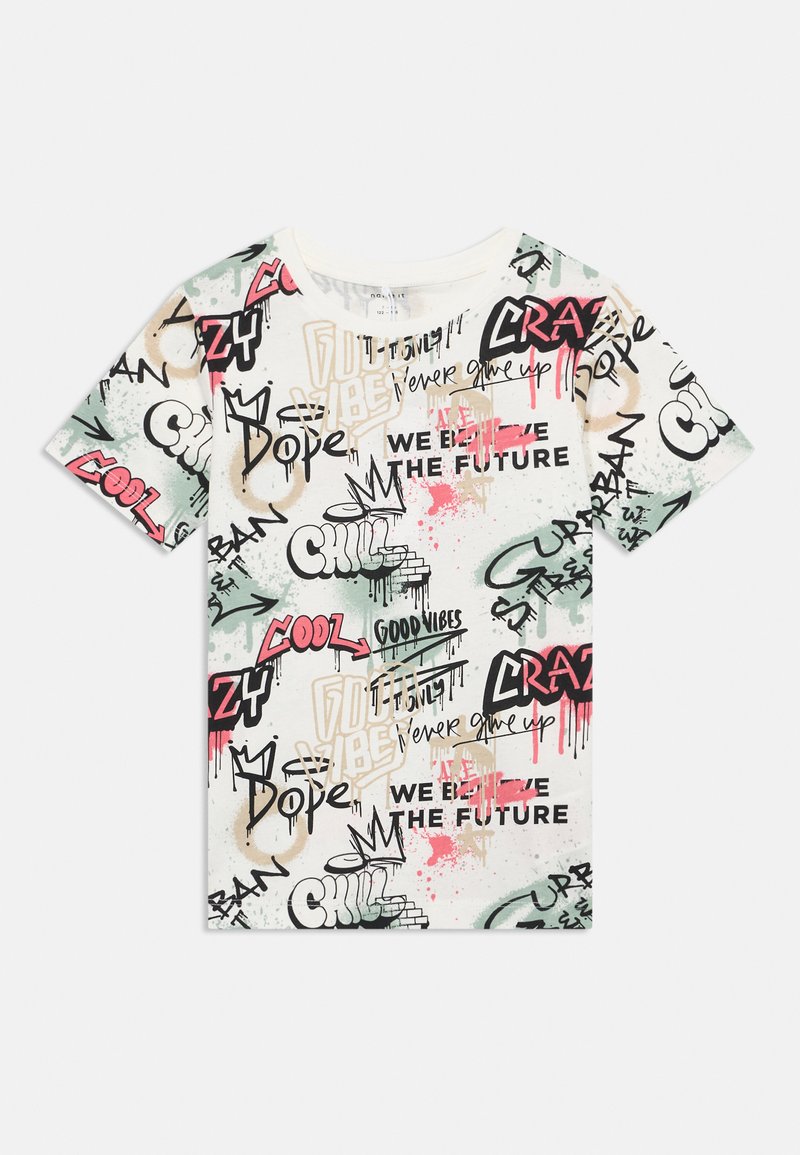 Kremskrāsas īsmafina T-kreklā ar krāsainiem grafiti stila rakstiem, kurā ir teksti kā "Dope", "Cool" un "Never give up" melnā, rozā un zaļā krāsā.
