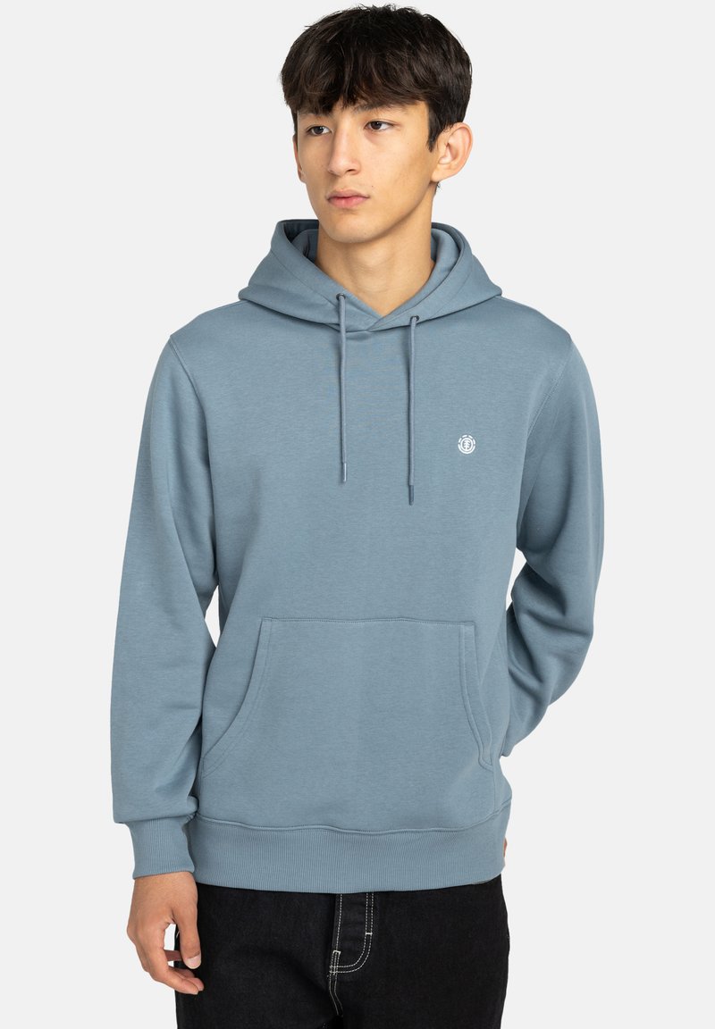 Svetlomodrá mikina s kapucňou vyrobená z mäkkej tkaniny, s predným vreckom, sťahovacou kapucňou a malým logom na hrudi. Uvoľnený strih.