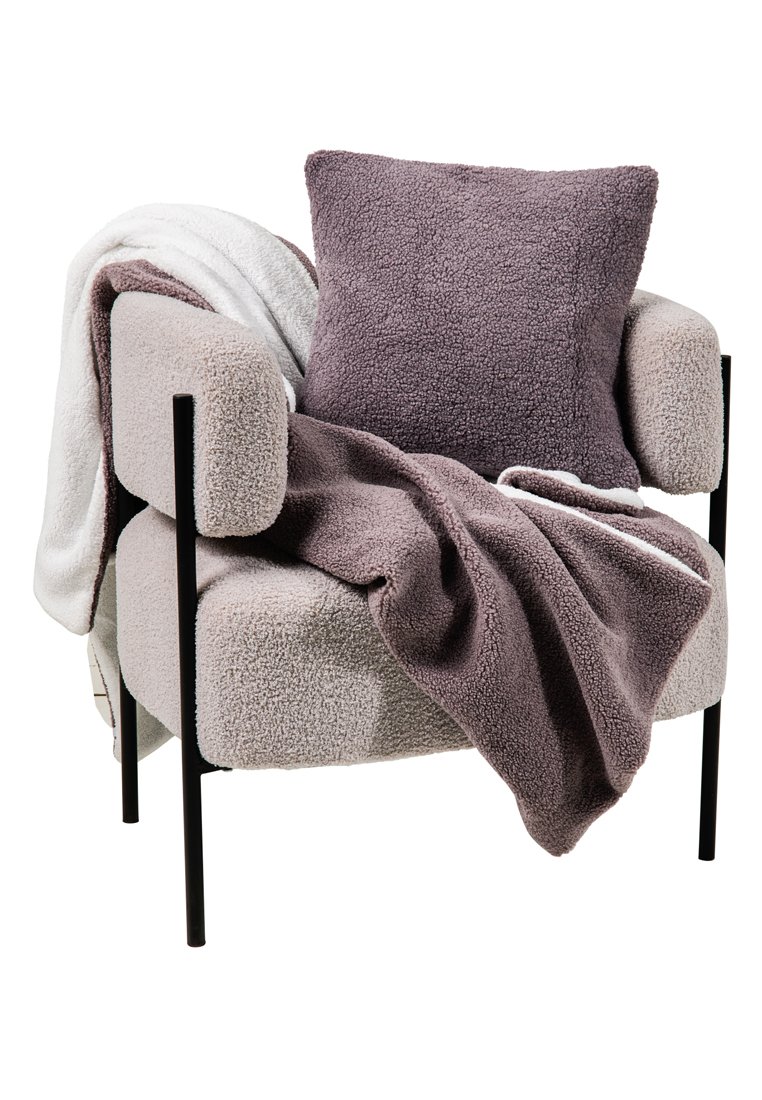 Beige Wolltextur-Sessel mit schwarzen Metallbeinen, mit einer mauve-farbenen Decke und einem passenden Kissen drapiert, sowie einer weißen Decke über einem Arm.