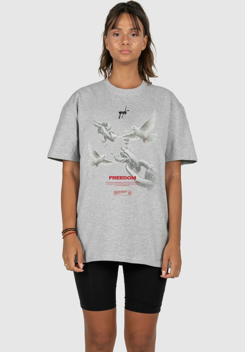 Graues, übergroßes T-Shirt aus Baumwolle mit einer Grafik von Tauben und Ketten, darunter dem Wort "FREIHEIT" in Rot.