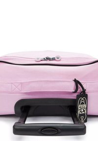 Borsa da viaggio rosa con manico telescopico nero, chiusura a zip, tessuto testurizzato e un'etichetta con un personaggio dei cartoni animati.