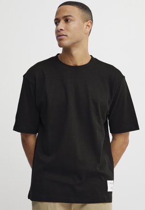 Black cotton t-shirt with short sleeves, crew neckline, and a straight cut. Features a small white label at the bottom left side.