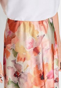 Gonna a fantasia floreale realizzata in tessuto leggero, con tonalità di rosa, arancione e verde, dotata di vita elastica e morbida al tatto.