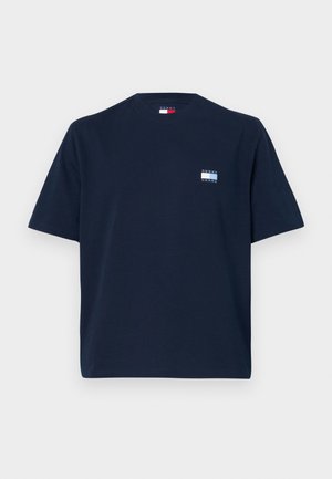 T-shirt in cotone blu navy con maniche corte, collo a giro, e una piccola etichetta con logo sul lato sinistro del petto con la scritta "TOMMY JEANS."