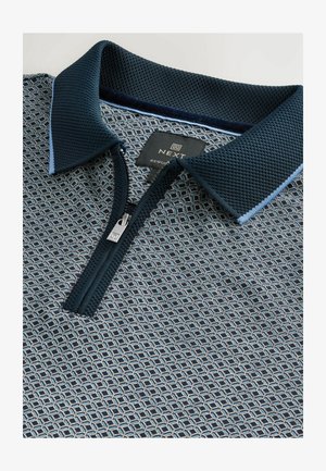 Mørkeblå polo shirt med mønster, med en lynlåslukning foran, struktureret krave og kontrastfarvede blå detaljer langs kraven.