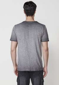 Šedé gradient tričko s krátkými rukávy, s kulatým výstřihem a měkkou, texturovanou tkaninou. Minimalistický design, bez viditelného loga.
