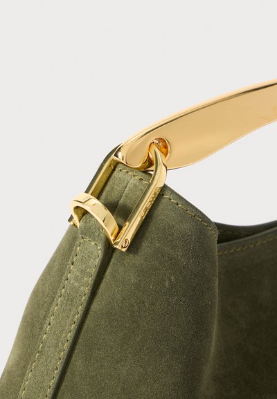 Zelena suknjena torbica s detaljima od pozlaćenog metala na remenu, vidljivim šavovima i glatkom teksturom.
