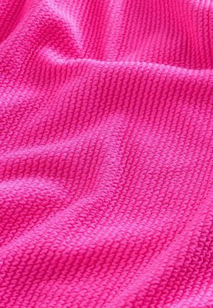 Texturált szövet élénk rózsaszínben, bordázott mintával. Puha és pelyhes megjelenés, finom fényességgel a szőtt szálaktól.