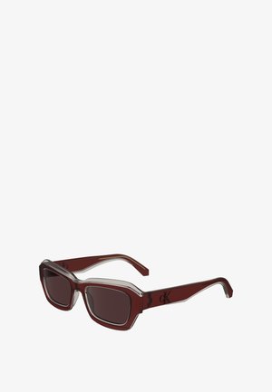 Solbriller med rødbrun plastikkramme, rektangulære linser, klare detaljer og en DK-logo på stilken. Har kraftig design og mørke linser.