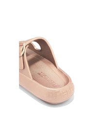 Sandalia de plástico rosa claro con una superficie texturizada, punta abierta y correa trasera. Presenta el nombre de la marca en relieve en la suela.