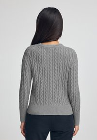 Maglione grigio a maglia grossa con orlo e polsini a coste, con un motivo testurizzato e scollatura rotonda, visto da dietro.