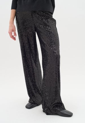 Black sequin wide-leg pants with a shiny texture, featuring a straight silhouette and a smooth waistband. Worn with black slip-on shoes.