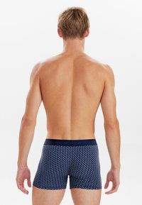 Navy blue boxer shorts with a geometric pattern, made from a smooth fabric, featuring a contrasting waistband and a fitted design.