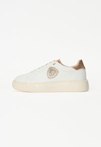 Sneaker bianco con una finitura liscia, dettagli dorati sul tallone e una toppa decorativa con il logo sul lato. Presenta una suola spessa e testurizzata.