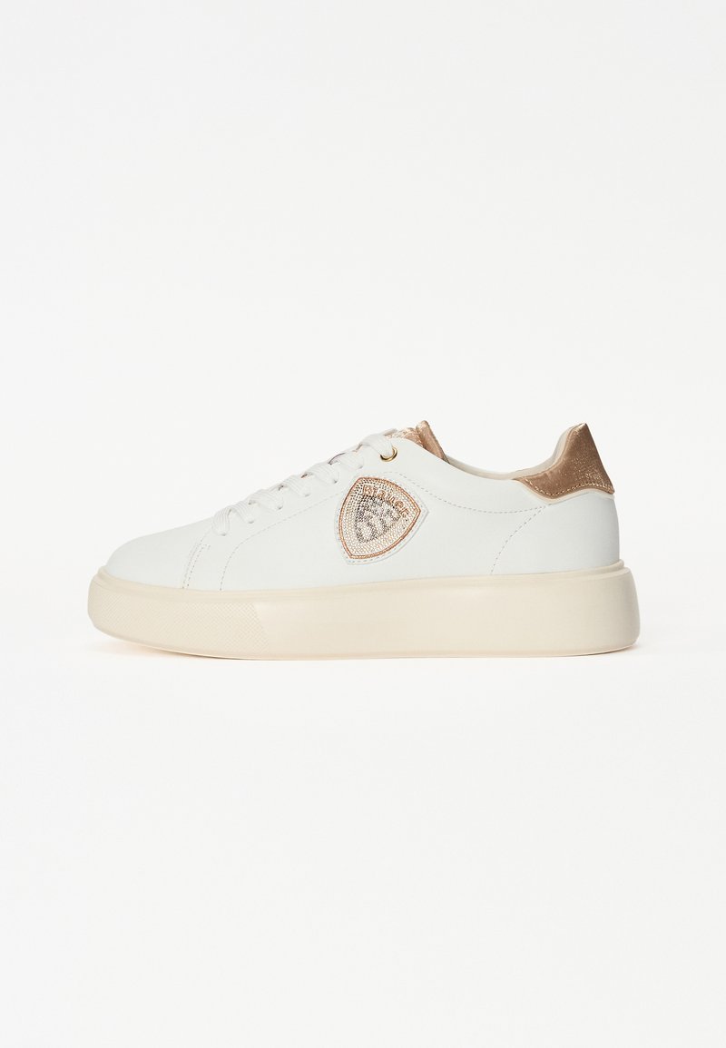 Sneaker bianco con una finitura liscia, dettagli dorati sul tallone e una toppa decorativa con il logo sul lato. Presenta una suola spessa e testurizzata.