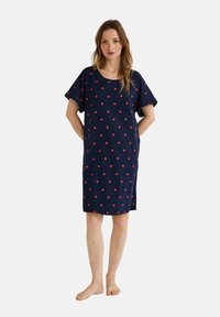 Robe en coton marine avec une coupe décontractée, des manches courtes et un motif de cœurs rouges sur l'ensemble ; longueur genoux avec un col rond.