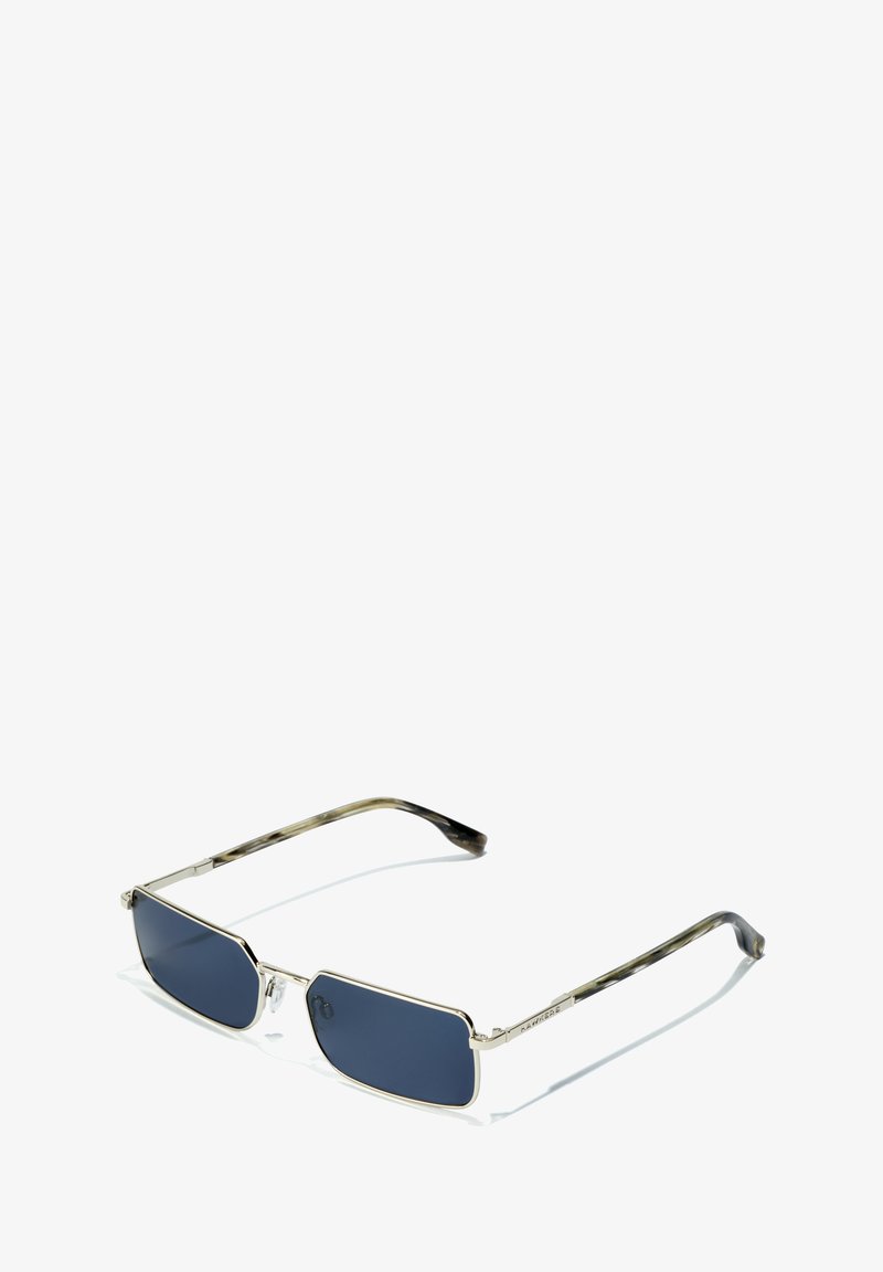 Zonnebril met een rechthoekige vorm, zilveren metalen frame, donkerblauwe glazen en een patroon op de zwarte en schildpadachtige pootjes.