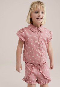 Conjunto de dos piezas de algodón rosa que incluye una camisa de manga corta con cuello y estampado floral, combinada con pantalones cortos con volantes.