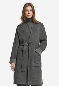 Grau melierter, langer Wollmantel mit einem Bindegürtel, der zwei Fronttaschen und Hahnentritt-musterte Bündchen aufweist. Glatte, weiche Textur.