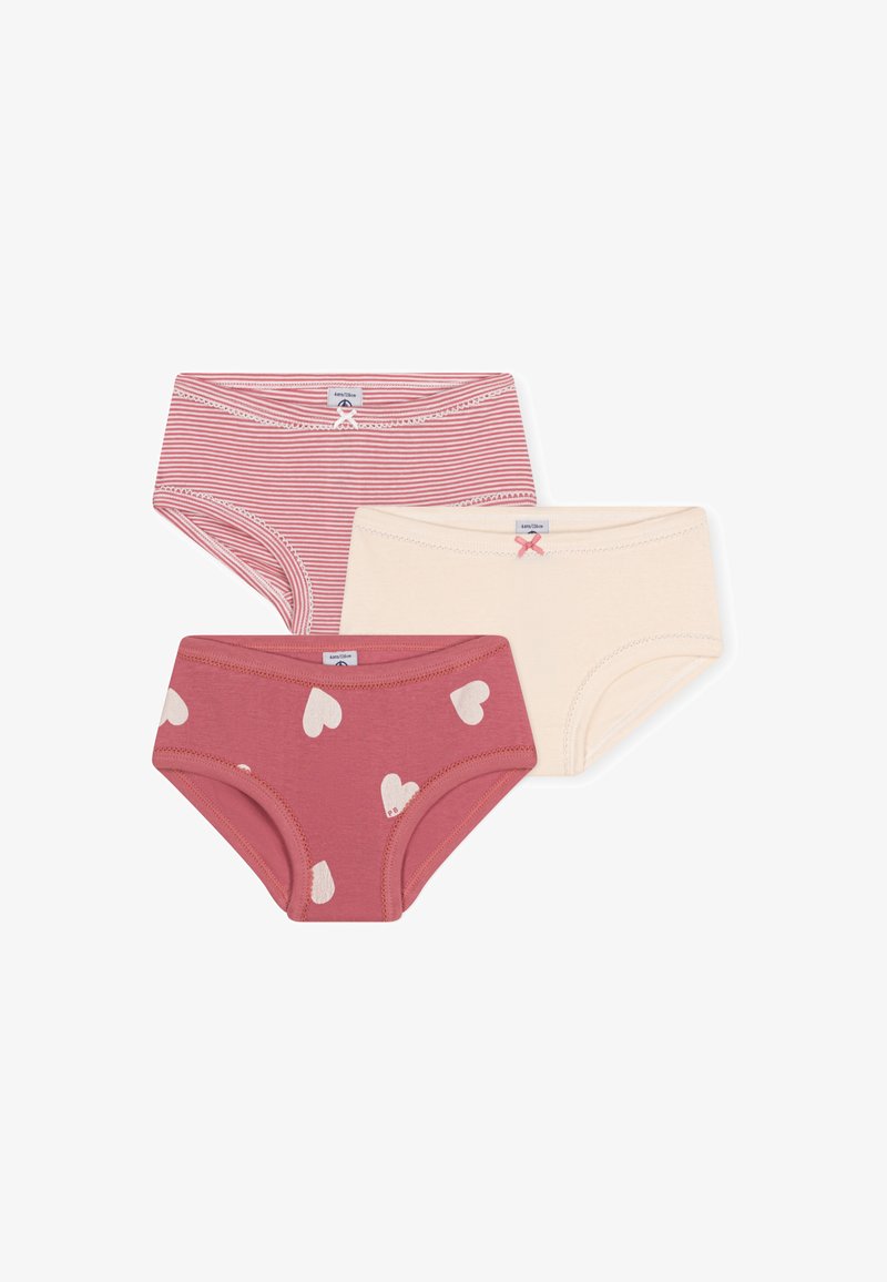 Três pares de roupa interior infantil: um riscado em vermelho, um sólido em rosa com corações brancos, e um creme com um detalhe em laço rosa. Tecido de algodão macio.