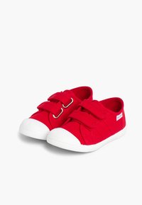 Zapatos de lona rojos con suelas de goma blanca, que presentan dos correas de velcro, una puntera redondeada y una superficie de tela texturizada.