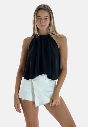 Top court noir à col halter avec un drapé lâche, associé à un short en denim blanc avec un design enroulé et un ourlet effiloché.