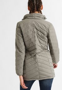 Quilted olive green jacket with a high collar, long sleeves, and diagonal stitching pattern. Features a fitted waist for a tailored look.