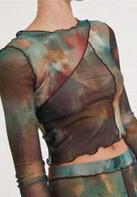 Průhledný top s dlouhým rukávem, který je zdobený mnohobarevným tie-dye vzorem v zelené, hnědé a červené barvě, se zoubkovanými okraji a přiléhavým střihem.