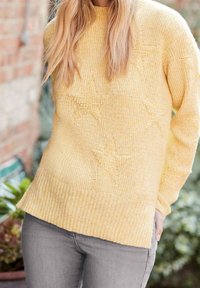 Pull en tricot jaune avec une texture côtelée et un motif d'étoiles. Le pull a une coupe décontractée et un col rond.