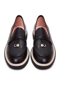 Mocassins en cuir noir avec semelles intermédiaires couleur crème, semelles extérieures texturées noires, et petites décorations argentées carrées et en anneau sur les brides.
