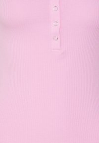 Ribbat rosa topp med en henley-krage och tre silverfärgade tryckknappar, tillverkad av mjukt, elastiskt material som är designat för en tight passform.