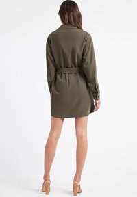 Vestido de camisa verde oliva con cinturón, mangas largas, puños de botón y un acabado de tela suave. Largo hasta el muslo con un diseño de cuello clásico.