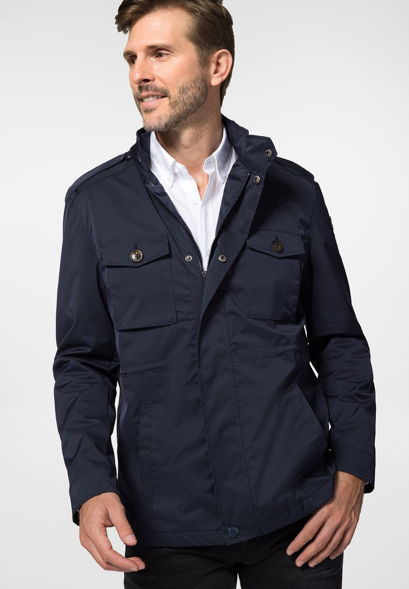 Granatowa, lekka kurtka z epoletami na ramionach, dwoma kieszeniami na piersi z klapkami na guziki oraz kieszeniami bocznymi; gładka struktura i zamek błyskawiczny.