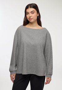 Maglione grigio oversize con ampia scollatura a barca, maniche lunghe e una texture morbida. Presenta una vestibilità comoda e un orlo arrotondato.