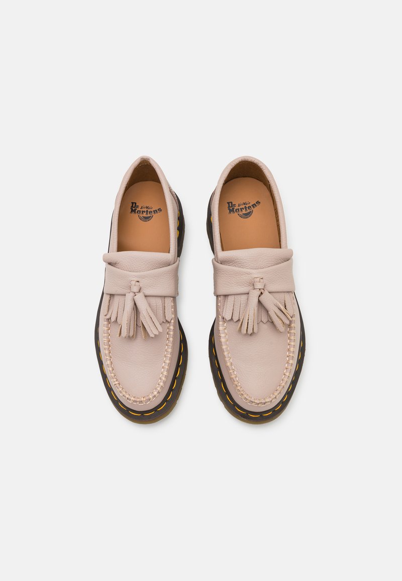 Mocassins en cuir rose clair avec des glands, semelle brune contrastante, couture jaune et semelle intérieure marquée. Texture lisse et forme arrondie.