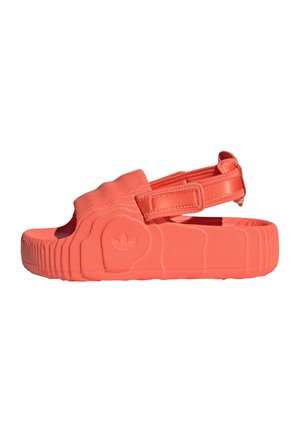 Koralfarvet sandal med åben tå, tyk sål, justerbar bagrem og tekstureret side med et diskret logo.