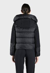 Zwarte pufferjas met een grote capuchon, gequilt textuur en elastische manchetten, met een cropped ontwerp en een gladde buitenstof.