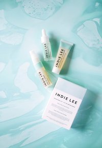 Tutkimuspaketti, joka sisältää kolme lasipulloa etiketeillä: kasvöljy, kasvovesi ja kirkastava puhdistusaine. Laatikkossa on teksti ja pehmeä, pastellisävyinen tausta.