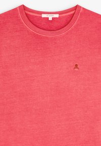 Rotes Baumwoll-T-Shirt mit Rundhalsausschnitt und einem kleinen braunen Totenkopf- und Kreuzschwert-Logo auf der Brust. Weicher Stoff, lässiges Design.