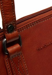 Borsa in pelle marrone con una texture liscia, dotata di una cerniera e hardware in metallo. Include dettagli cuciti e logo impresso.