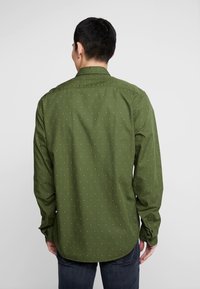 Grüne Hemd mit kleinen, gemusterten Punkten, mit Knopfmanschetten und klassischem Kragen. Glatte Stoffqualität und leicht taillierte Passform.