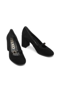 Melna zamšāda augstpapēžu apavi ar kvadrātu formas purngalu, ar Mary Jane siksniņu un zelta aksesuāru, kā arī masīlu papēdi. Gluda tekstūra.