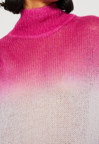 Pull en tricot rose à col montant, présentant un dégradé du rose vif au blanc, avec une texture douce, légère et légèrement transparente.