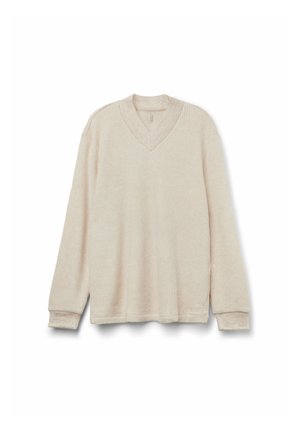 Beige stickad tröja med V-hals, lång ärm och ribbat mönster. Har en avslappnad passform och subtila sömnadsdetaljer.